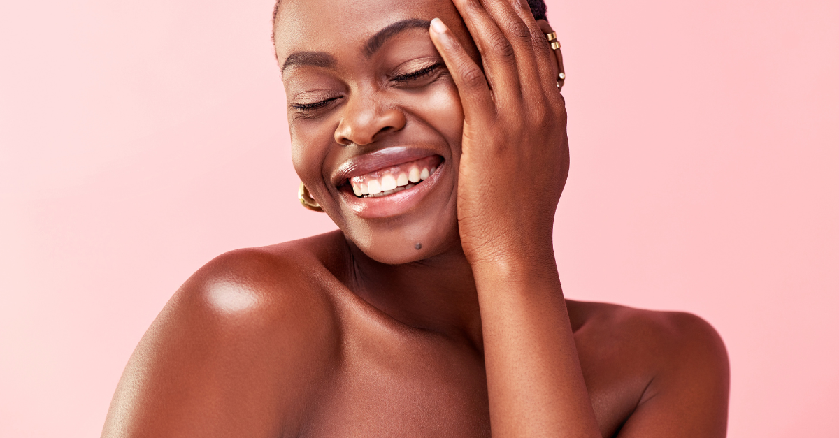 Smiling woman with glowing skin, representing healthy summer skincare routine.